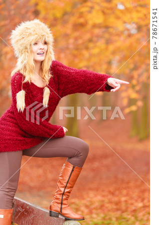 Pretty smiling woman in fur winter hat pointing. 78671541