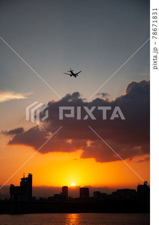 夕陽に染まる空に飛ぶ飛行機 78671831