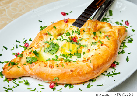 Ajarian traditional flatbread khachapuri or hachapuri with cheese, egg and butter on a plate 78671959