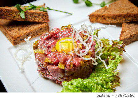 Veal tartar with quail egg and rye toast. Close-up, selective focus 78671960