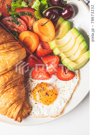 Breakfast plate with croissant, avocado, fried egg, salad and fruit. Breakfast plate with croissant, avocado, fried egg, salad and fruit. 78673232