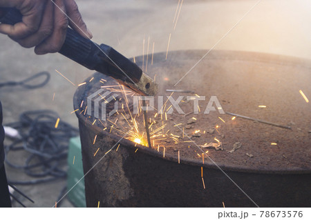 The technical Industry worker welding iron pieces tank at work with a spark flash light 78673576