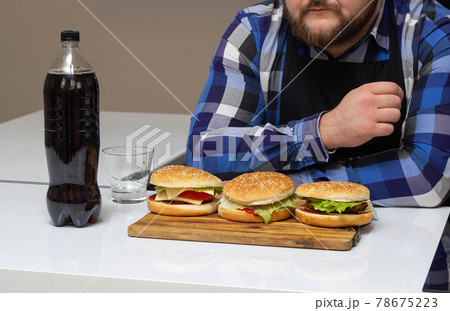 A man with a beard sits and looks at burgers with harmful soda, background, cheeseburger A man with a beard sits and looks at burgers with harmful soda, background, cheeseburger 78675223
