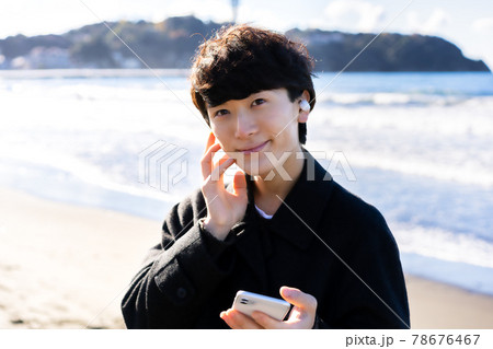 海でスマホの音楽を聴く男性 78676467
