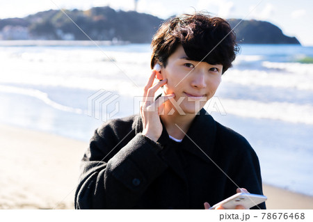海でスマホの音楽を聴く男性 78676468