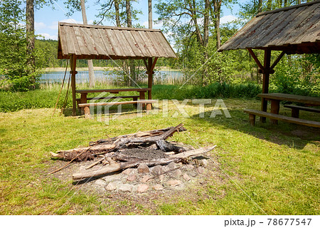 Bonfire and picnic area in a forest by a lake. Bonfire and picnic area in a forest by a lake. 78677547