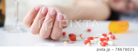 Bride in wedding dress lying on couch with handful of pills in her hand closeup 78678025