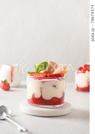 Layered dessert in glass jars with cookie savoyardi, mascarpone and whipped cream decorated strawberries Layered dessert in glass jars with cookie savoyardi, mascarpone and whipped cream decorated strawberries 78679374
