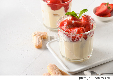 Layered strawberry dessert in glass jars with savoyardi, mascarpone on white. 78679376