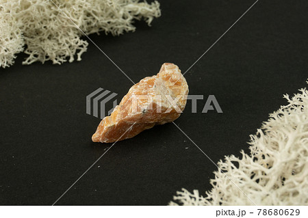 Orange Calcite from Brazil. Natural mineral stone on black background. Mineralogy, geology, magic of stones, semi-precious stones and samples of minerals. Close-up macro photo. 78680629