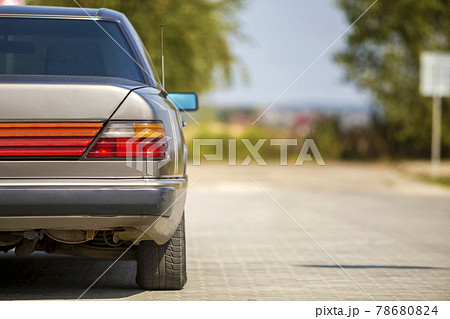 Back view of silver car parked on paved street in quiet area on sunny bright background. Transportation and urban parking concept. Back view of silver car parked on paved street in quiet area on sunny bright background. Transportation and urban parking concept. 78680824
