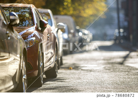 Long row of different shiny cars and vans parked along empty roadside on sunny autumn day on blurred green golden foliage bokeh background. Modern city lifestyle, vehicles parking problem concept. 78680872