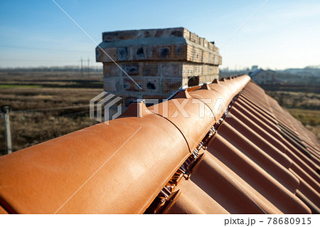 Closeup of yellow ceramic roofing ridge tiles on top of residential building roof under construction. Closeup of yellow ceramic roofing ridge tiles on top of residential building roof under construction. 78680915