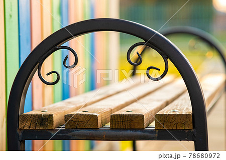 Closeup of wooden park bench with metal handgrip outdoors. 78680972