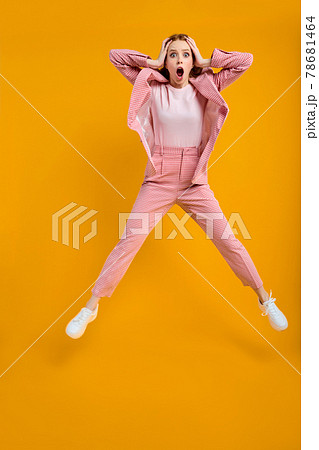 Surprised wondered redhead business lady jumping omg expression, isolated on yellow Surprised wondered redhead business lady jumping omg expression, isolated on yellow 78681464