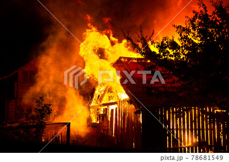 Wooden house or barn burning on fire at night. 78681549