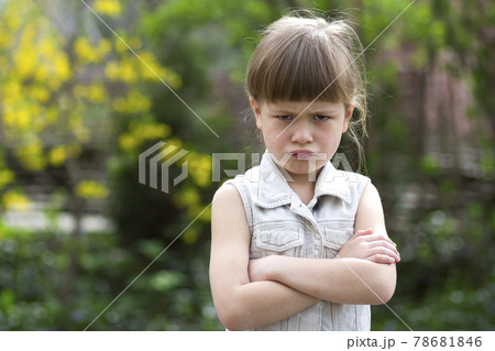 Pretty funny moody little blond preschool girl in white sleeveless dress looks into camera feeling angry and unsatisfied on blurred summer background. Children tantrum concept. Pretty funny moody little blond preschool girl in white sleeveless dress looks into camera feeling angry and unsatisfied on blurred summer background. Children tantrum concept. 78681846