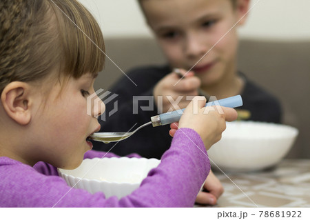 Two children boy and girl eating soup 78681922