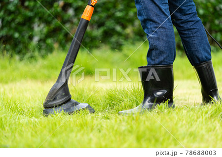 worker using a string lawn trimmer mower cutting grass 78688003