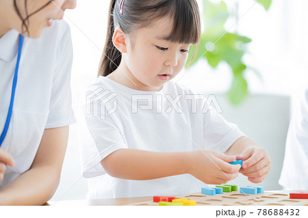 幼児教室 英語学習 アルファベットのブロックを型にはめる女の子の写真素材