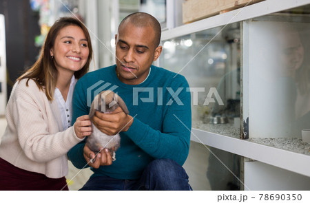 Family couple holding rabbit together in pet shop 78690350