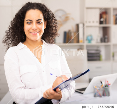 Young businesswoman with clipboard politely welcoming to company office 78690646
