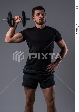 Sporty young man doing dumbbell one arm shoulder press Sporty young man doing dumbbell one arm shoulder press 78692116