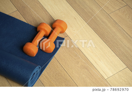 Yoga and fitness background. Wooden floor parquet or laminate with rug and dumbbells for training in a yoga room or gym 78692970