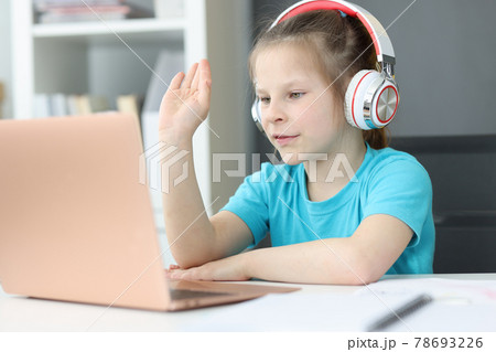 Smiling pretty cute little 6 year old girl in headphones looking at laptop screen Smiling pretty cute little 6 year old girl in headphones looking at laptop screen 78693226