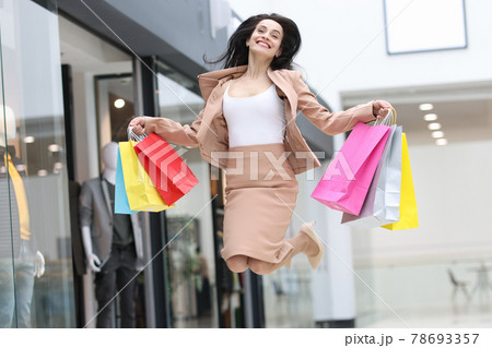 Emotionally happy woman jumping with shopping bags in mall 78693357