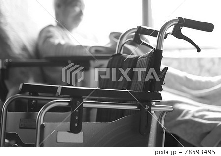 介護ベッドでくつろぎながらタオルケットをいじる認知症の高齢女性と車椅子 78693495