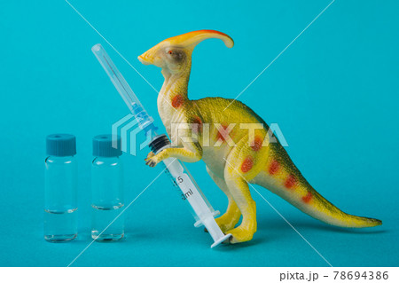 minimal concept of vaccination against coronavirus, protection against extinction of the population, a toy dinosaur holds a syringe and a vaccine stands nearby 78694386