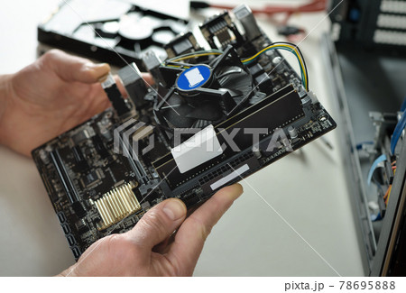 A technician is holding the motherboard in a desktop case. 78695888