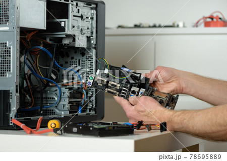 A technician is holding the motherboard in a desktop case. 78695889