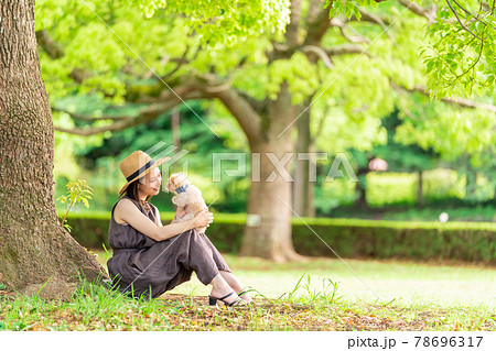 小型犬と一緒に散歩する若い女性　柏の葉公園 78696317
