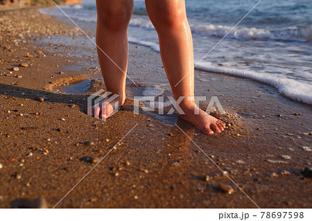 little baby feet stand in the sand by the sea. close-up 78697598