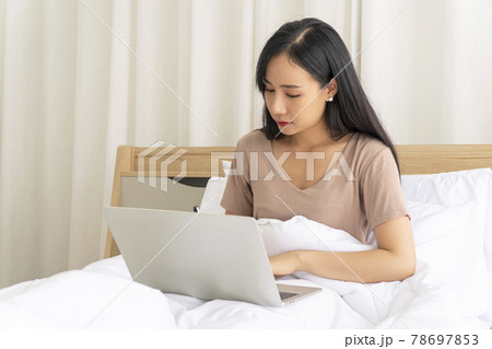 Freelance young woman using laptop working on internet write something on the book  78697853