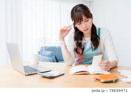 レシートを確認しながら家計簿をつけ家計のやりくりに悩む女性 レシートを確認しながら家計簿をつけ家計のやりくりに悩む女性 78699471