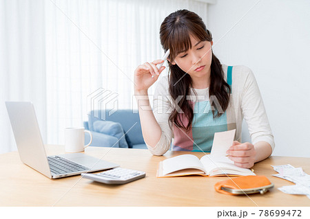 レシートを確認しながら家計簿をつけ家計のやりくりに悩む女性 78699472