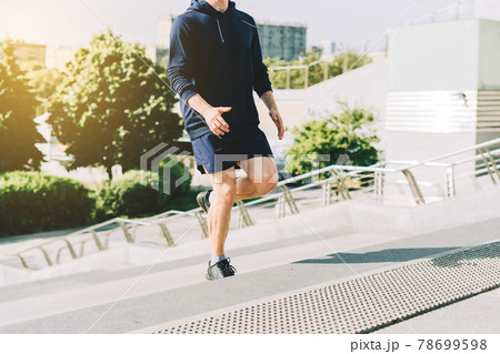 Young athlete man runner running up stairs on city stairs in summer on morning run, background urban city street. Sports training. Fitness cardio workout in fresh air, walk outside. 78699598