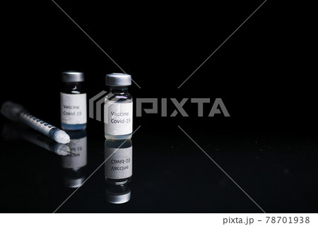 Close up of coronavirus vaccine and syringe on black background 78701938