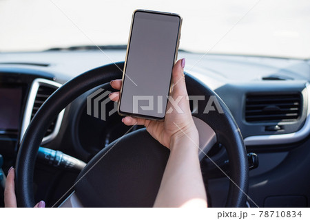 A faceless woman uses a mobile phone while driving a car. The girl uses the navigation in the smartphone 78710834