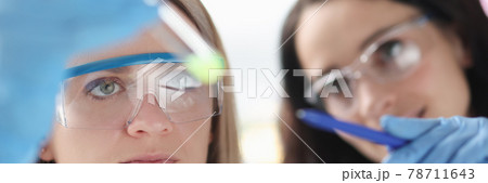Two female scientists in laboratory examine test tube with liquid Two female scientists in laboratory examine test tube with liquid 78711643
