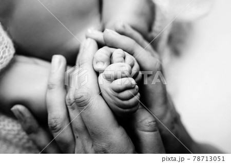 Children's feet in hold hands of mother and father on white. Mother, father and newborn Child. Happy Family people concept. Black and white. 78713051
