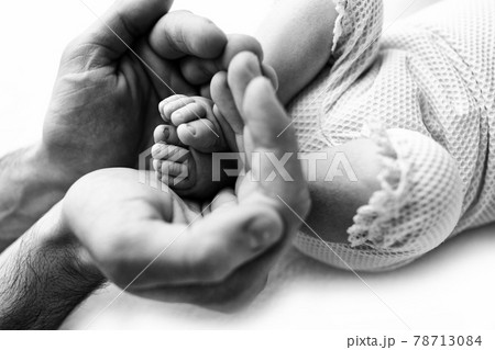 Feet of a newborn in the hands of a father, parent. Black and white.  78713084