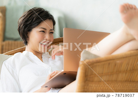 椅子の上でパソコンを使う若い女性 椅子の上でパソコンを使う若い女性 78719037