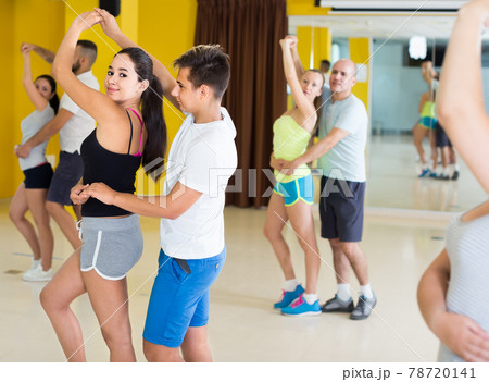 sporty girls and men learning salsa steps 78720141