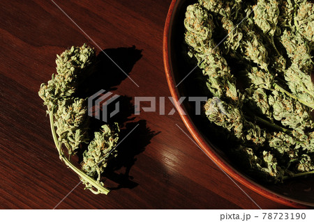Marijuana buds storage. Medicinal cannabis flowering on brown wooden background, isolated. Marijuana buds storage. Medicinal cannabis flowering on brown wooden background, isolated. 78723190