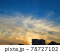青空の下、建物と雲に隠れる夕日 78727102