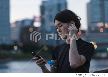 屋外で音楽を聞きながらランニングの準備をする若い男性 屋外で音楽を聞きながらランニングの準備をする若い男性 78727983